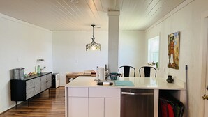 A modern kitchen with a central island, white cabinetry, and a stainless steel dishwasher.