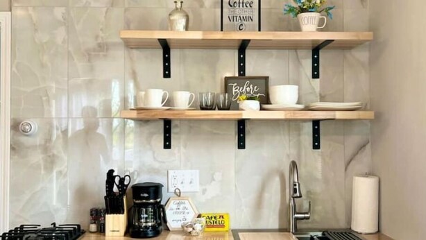 Une cuisine avec trois étagères en bois, une machine à café et un panneau sur lequel on peut lire : « Le café, c’est l’autre vitamine C ».