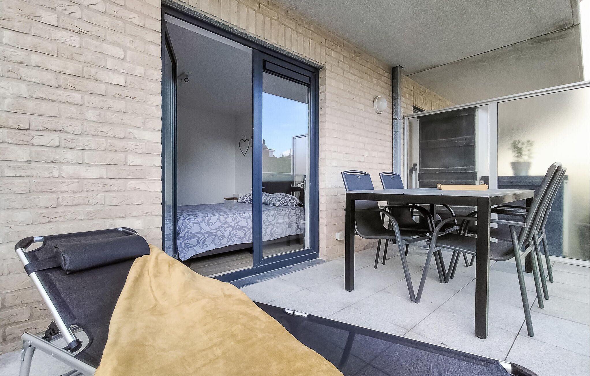 A room with a bed, a table with chairs, and a sliding door leading to another room.