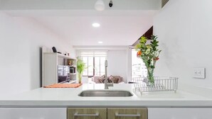 Una cocina moderna con encimeras blancas, un fregadero de acero inoxidable y armarios de madera.