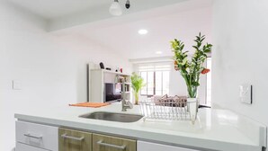 Una cocina moderna con un lavamanos de acero inoxidable, armarios de madera y encimera blanca.