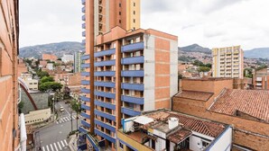 Un edificio de gran altura con varios balcones, una calle debajo y un paisaje montañoso al fondo.