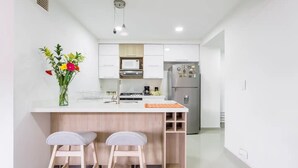 Una cocina moderna con armarios blancos, un refrigerador de acero inoxidable y una isla de madera con taburetes de bar.
