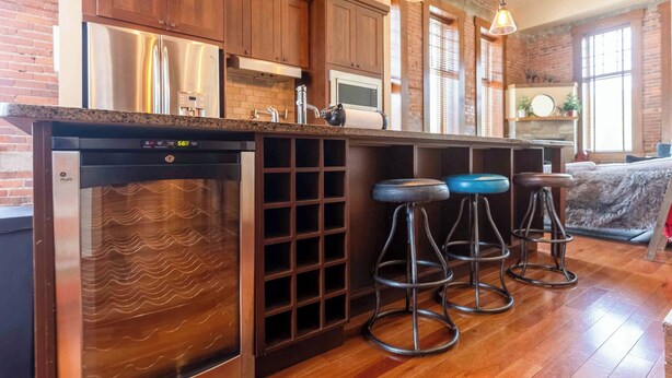 A kitchen with a dishwasher, stainless steel appliances, and a bar area with stools. - Beautiful 3 Bedroom l Sleeps 5 (Fernie)