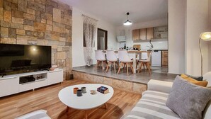 Ein modernes Wohnzimmer mit Steinwand, Flachbildfernseher, weißem Couchtisch und gestreifter Couch.