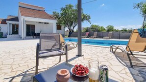Ein Poolbereich mit Liegestühlen, einem Tisch mit einer Schale Kirschen, einem Bierglas und einer Bierdose.