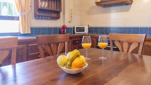 A wooden dining table with a bowl of fruit and two glasses of orange juice. - Bellavista Arriate by Ruralidays (Málaga)