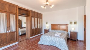 A bedroom with a large bed, wooden wardrobe, and two bedside tables with lamps. - Bellavista Arriate by Ruralidays (Málaga)