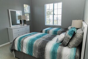 Un dormitorio con dos camas, un aparador, un espejo y dos ventanas.