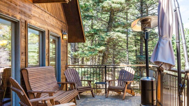 Un’area esterna con una terrazza in legno, poltrone Adirondack, un tavolino e un bidone.