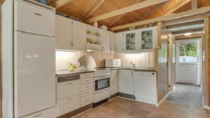 Una cocina compacta con armarios blancos, horno empotrado, microondas y lavavajillas.