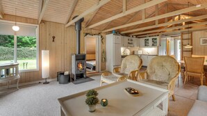 Un acogedor interior de cabaña con chimenea, muebles de mimbre y vistas al exterior.
