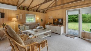 Una habitación acogedora con sofá, sillas, televisor y ventana con vistas a un jardín.