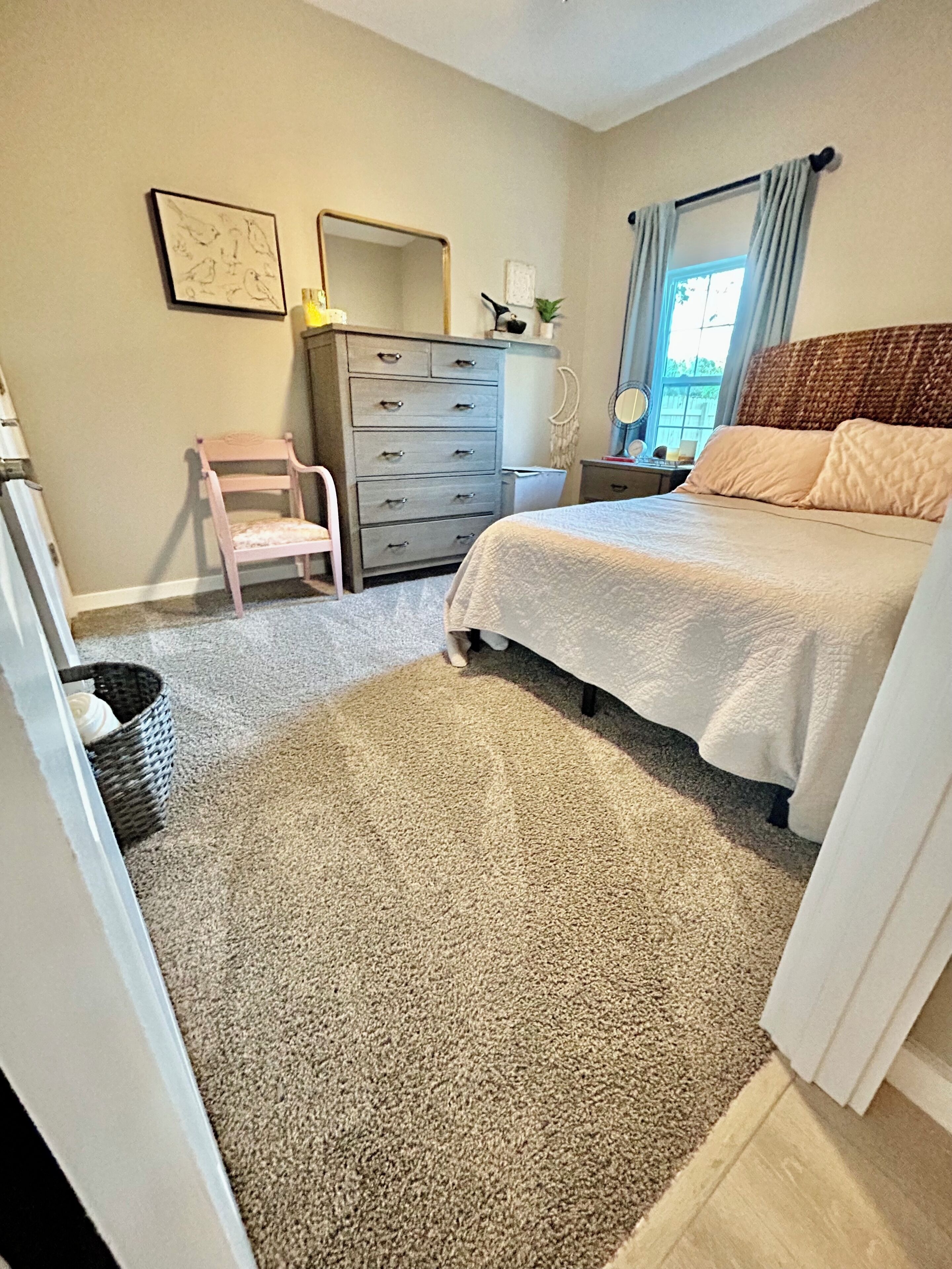 Une chambre à coucher avec un lit, une commode, une chaise et un grand miroir.
