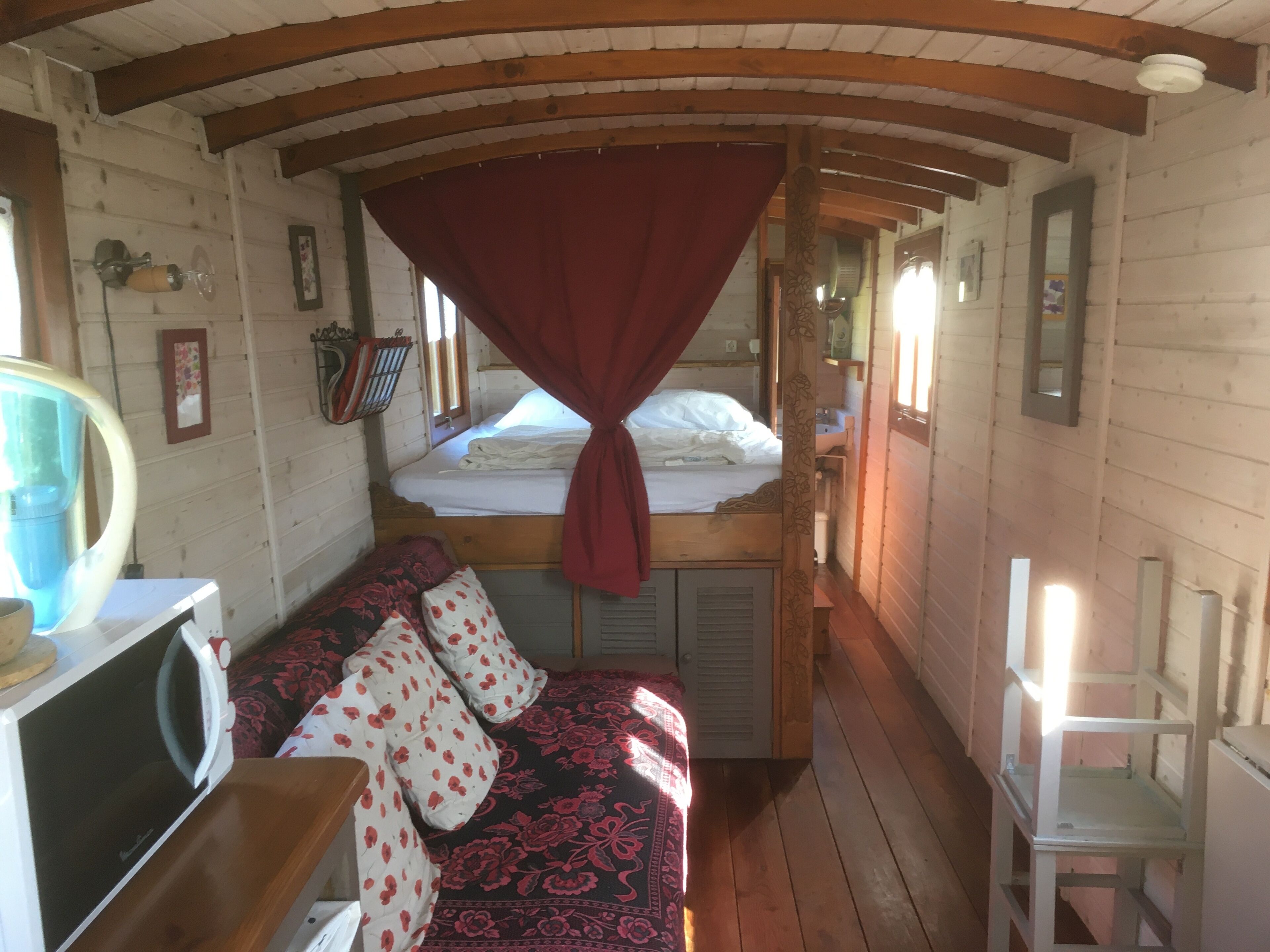 Une cabine équipée d’un lit superposé, d’un canapé avec des coussins à motifs, d’un four à micro-ondes et d’une petite table.