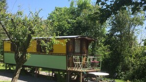 Een houten hut met een balkon, een tafel en stoelen in een tuin.