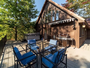 Une terrasse en bois avec des meubles d’extérieur, un barbecue et un jacuzzi.