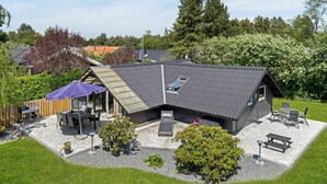 A modern house with a sloped roof, outdoor seating area, and a patio. - Stunning home in Rødby with kitchen (Rødby)