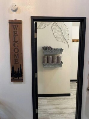 Welcome to a serene hallway with a decorative wall featuring a leaf pattern, complete with a convenient shelf for storing essentials.