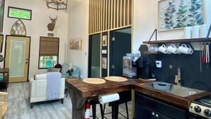Une cuisine moderne avec un îlot central en bois, des meubles de rangement noirs et un four encastré.