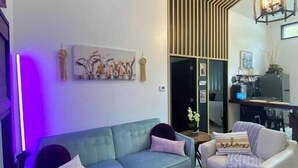 Un salon moderne avec un canapé de couleur turquoise, un fauteuil blanc, un banc en bois et une décoration murale représentant une tête de cerf.
