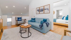 Una sala de estar moderna con un sofá azul, una mesa de centro redonda y un ventanal grande.
