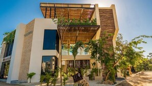 A modern building with a flat roof, large windows, and a mix of natural and artificial materials. - Fantastic Apartment with Private Pool · 305 (Tulum)