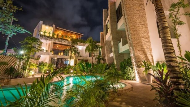 A modern hotel with a pool, surrounded by lush greenery and palm trees. - Fantastic Apartment with Private Pool · 305 (Tulum)
