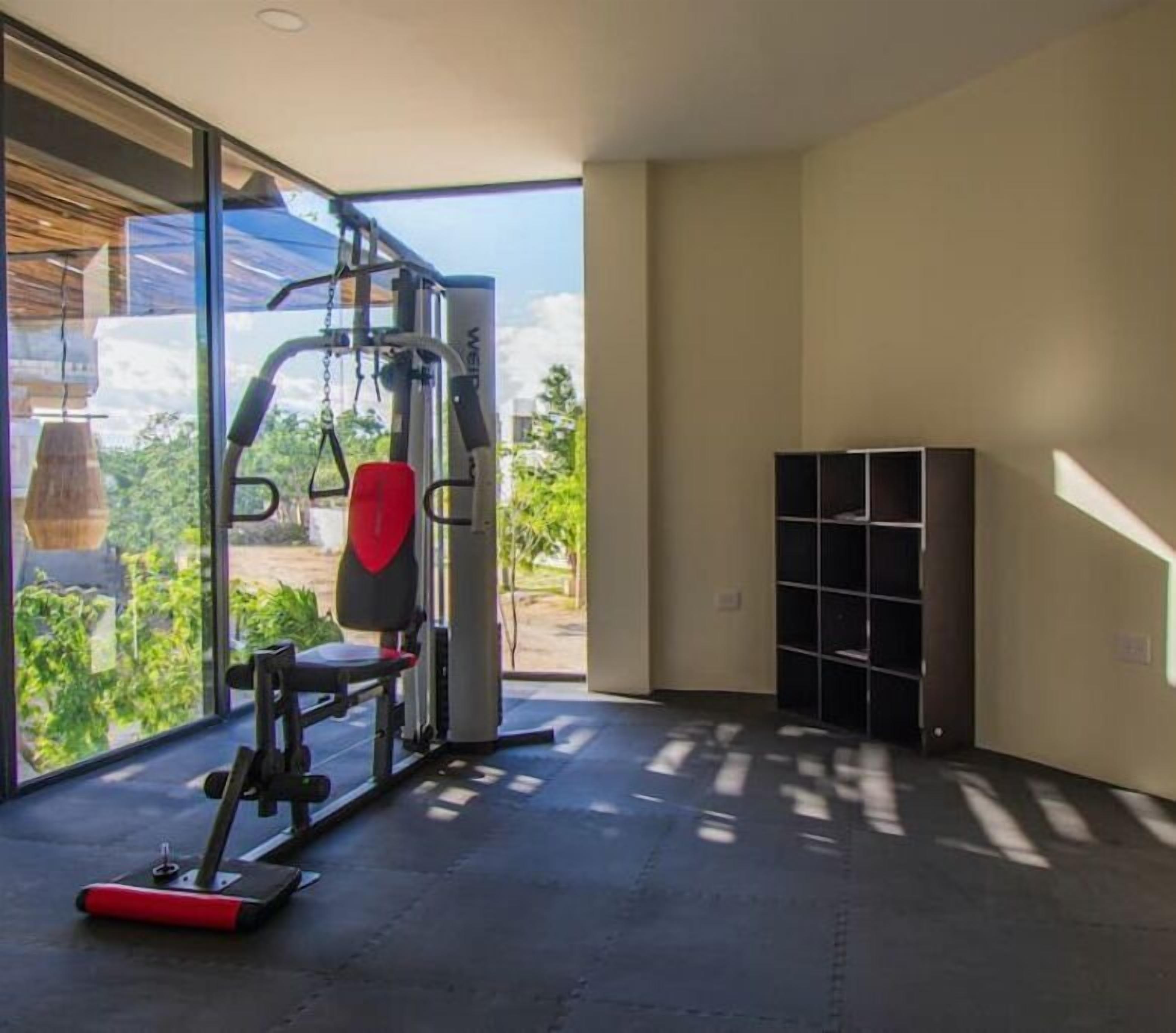 Ein Fitnessraum mit Squat-Rack, rotem Gewichtsheberbank und Klimmzugstange.