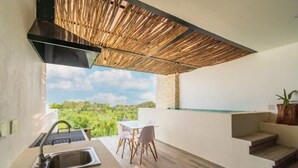 A modern outdoor kitchen with a sink, a table, and chairs, overlooking a lush green landscape. - Fabulous Apartment With Private Pool · 306 (Tulum)
