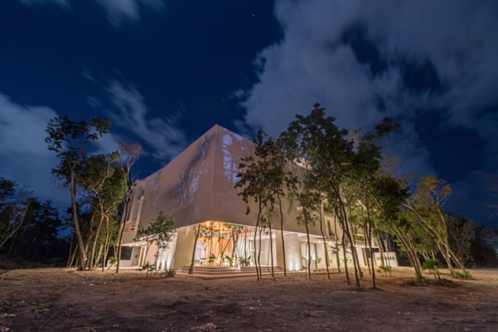 En modern byggnad med en unik, pyramidliknande struktur, omgiven av träd.