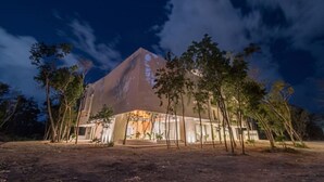 En moderne bygning med en unik pyramideformet struktur, omgivet af træer.