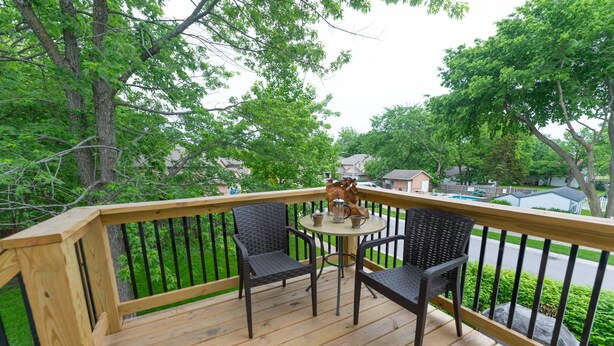 A wooden deck with a table and two chairs, surrounded by a black railing. - Vintage Space! 60 Seconds from Downtown Lee Summit (Lee's Summit)