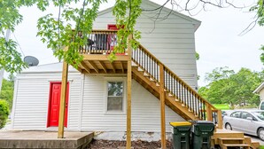 A single-story house with a red door, a wooden staircase leading to a balcony, and a satellite dish on the roof. - Vintage Space! 60 Seconds from Downtown Lee Summit (Lee's Summit)