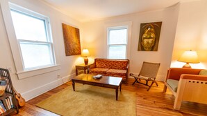 A living room with a sofa, armchair, coffee table, and lamps. There are bookshelves and a statue on the wall. - Vintage Space! 60 Seconds from Downtown Lee Summit (Lee's Summit)