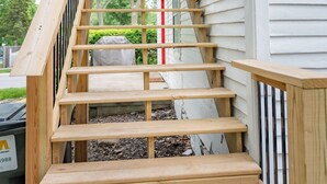 A wooden staircase leading to a deck with a railing, adjacent to a white building. - Vintage Space! 60 Seconds from Downtown Lee Summit (Lee's Summit)