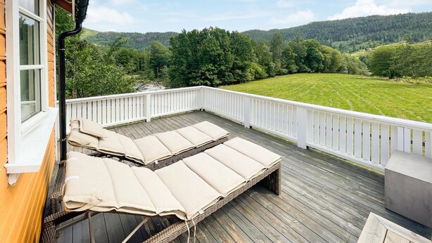 Une terrasse dotée de chaises longues et offrant une vue sur un paysage verdoyant.