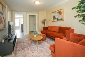 Una sala de estar con un sofá, una mesa de centro y un televisor sobre un mueble.
