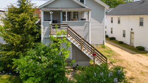 A two-story house with a porch, a staircase, and a small garden area. - Apartment in town center #1 (West Brookfield)