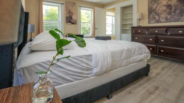 A bedroom with a bed, a nightstand, a dresser, and a window. - Apartment in town center #1 (West Brookfield)