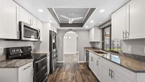 Une cuisine moderne avec des armoires blanches, des appareils en acier inoxydable et un plancher en bois.