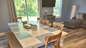 Comedor con una mesa dispuesta para cuatro personas, rodeado de sillas de madera con asientos acolchados.