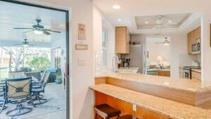 A modern kitchen with granite countertops, wooden cabinets, and a built-in oven. - Palm Paradise Poolside (Cape Coral)
