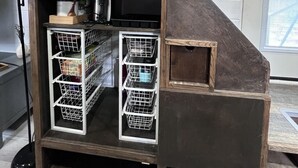 A staircase with built-in storage compartments and a wall-mounted sign. - Unique Tiny Home Escape! Fully Equipped & Relaxing, Privacy-Fenced Outdoor Space (Raleigh)