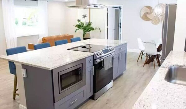 A modern kitchen with a central island, built-in oven, and stainless steel appliances.