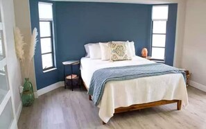 Relax in this serene bedroom with a large bed, bedside table, and large window.
