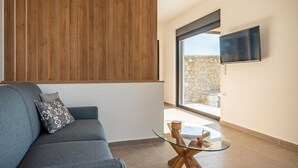 Ein modernes Wohnzimmer mit grauem Sofa, einem Glastisch und einer Wandpaneele aus Holz.