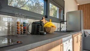 Eine Küche mit modernem Design, ausgestattet mit einer integrierten Waschmaschine, einer Kaffeemaschine und einem Obstkorb auf der Arbeitsfläche.