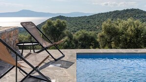 Ein Poolbereich mit Liegestühlen und Blick auf eine Berglandschaft.