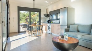 A modern kitchen with a built-in washing machine, a dining area with a table and chairs, and a living area with a sofa and coffee table.